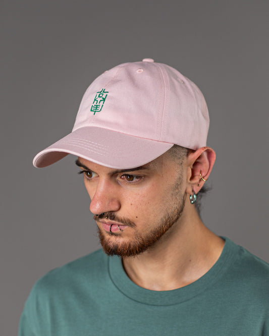 Frontalansicht der pinkfarbenen Cap mit grünem LOKEY-Sticklogo in klar lesbarer Vertikalform. Der Träger blickt nach unten, das Design ist zentriert auf der Vorderseite der Cap.