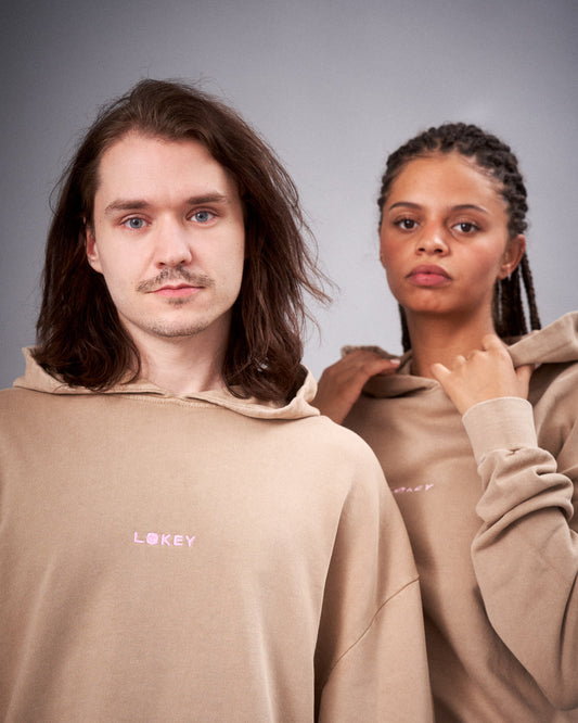 Zwei Personen tragen den beigefarbenen Hoodie mit LOKEY-Schriftzug auf der Brust, frontal fotografiert.