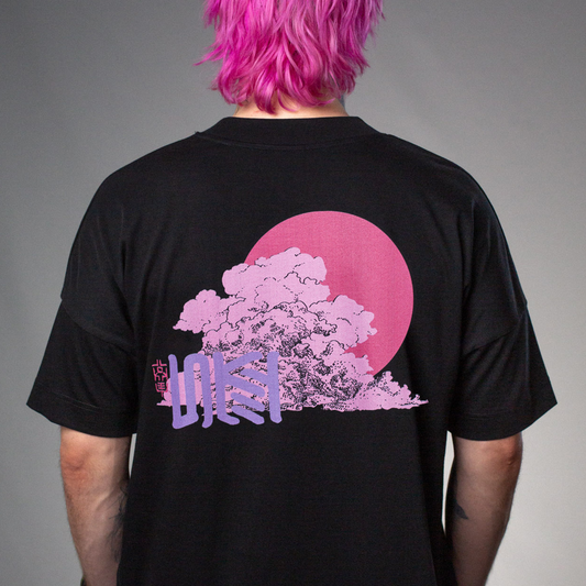 Schwarzes T-Shirt mit großem, pink-violettem Rückendruck: Eine stilisierte Baumkrone in Wolkenform vor einer kreisrunden pinken Sonne. Darauf sitzt ein vertikaler, violetter Schriftzug in japanischer Typografie. Links daneben ist ein kleiner roter Stempel mit asiatisch anmutenden Zeichen platziert.